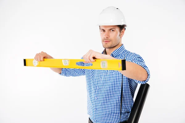 Allvarlig man byggnadsingenjör i hård hatt med vattenpass — Stockfoto