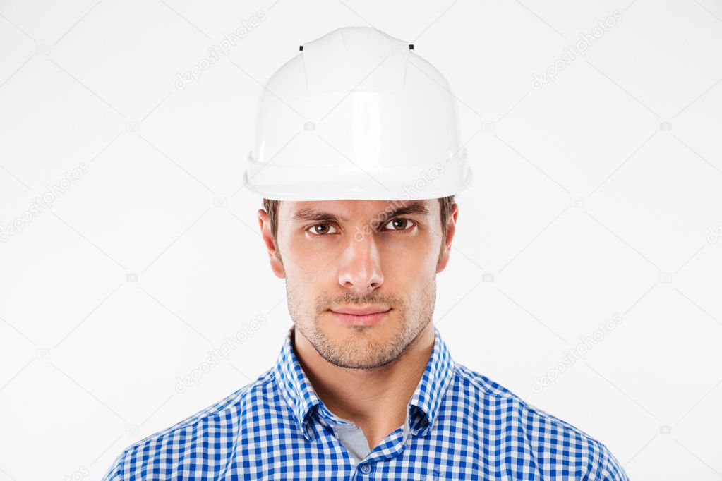 Portrait of serious young man architect in building helmet