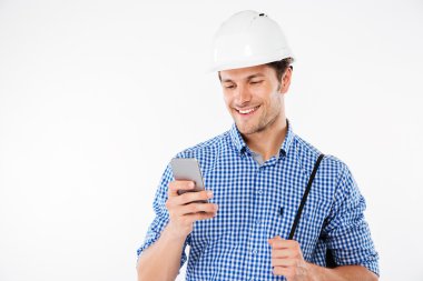 Gülümseyen genç mimar cep telefonu kullanıyor.