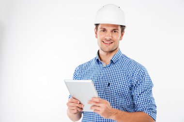 Neşeli adam mimar ayakta ve tablet kullanarak zor şapka