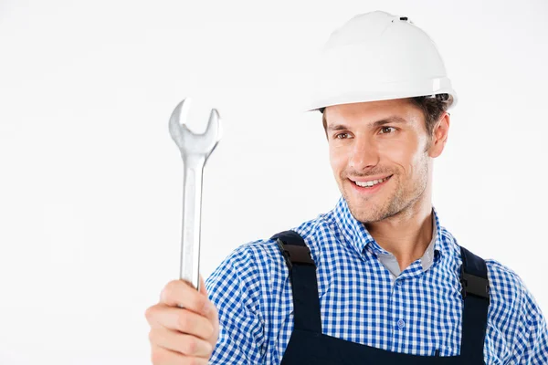 Sorrindo masculino bonito construtor segurando chave inglesa — Fotografia de Stock