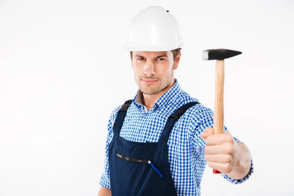 Щасливий молодий будівельник в шоломі стоїть і тримає молоток — стокове фото