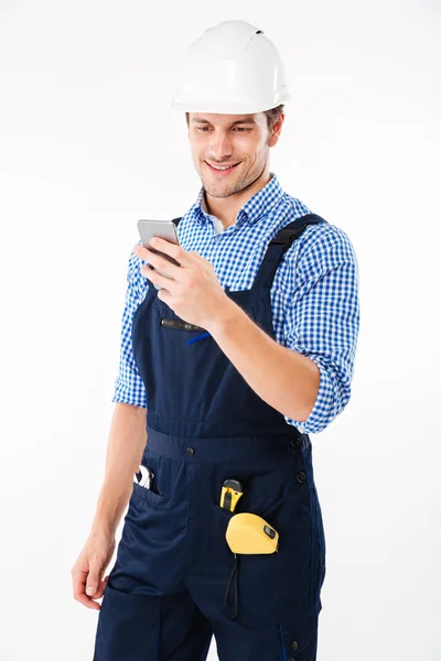 Портрет красивого строителя, стоящего и пользующегося мобильным телефоном — стоковое фото