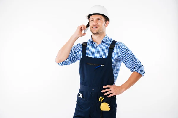 Красивый молодой строитель в целом разговаривает по мобильному телефону — стоковое фото