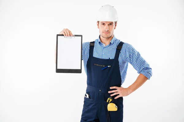 Серьезный красивый строитель с чистым листом бумаги на планшете — стоковое фото