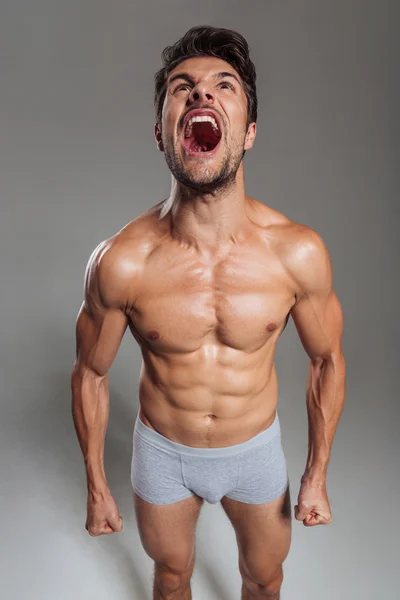 Muscular young brunette man wearing underwear shouting — Stock Photo, Image