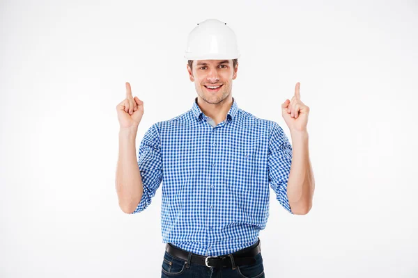 Joven constructor alegre en sombrero duro apuntando hacia arriba —  Fotos de Stock