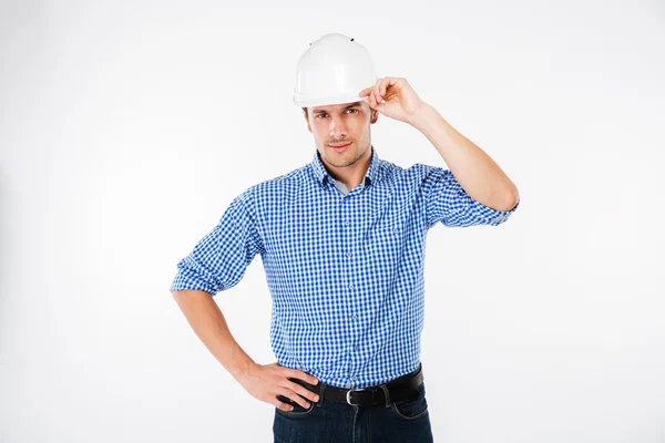 Allvarlig ung man byggnadsingenjör i hård hatt poserar — Stockfoto