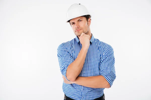 Fundersam ung man builder i hård hatt standng och tänkande — Stockfoto