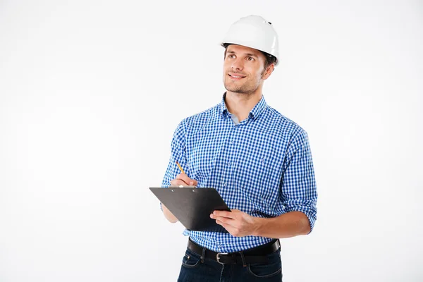 Ingeniero de construcción de hombre en la escritura de sombrero duro en portapapeles —  Fotos de Stock
