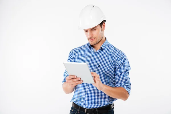 Ernstige man architect in harde hoed permanent en het gebruik van Tablet PC — Stockfoto