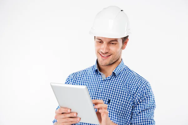 Χαμογελαστός νεαρός κτίριο μηχανικός στο κράνος χρησιμοποιώντας tablet — Φωτογραφία Αρχείου