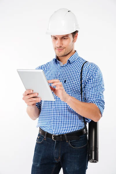 Человек строитель в каске стоя и с помощью планшета — стоковое фото