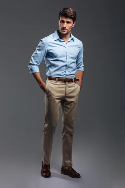 Handsome young man standing with hands in pockets — Stock Photo, Image