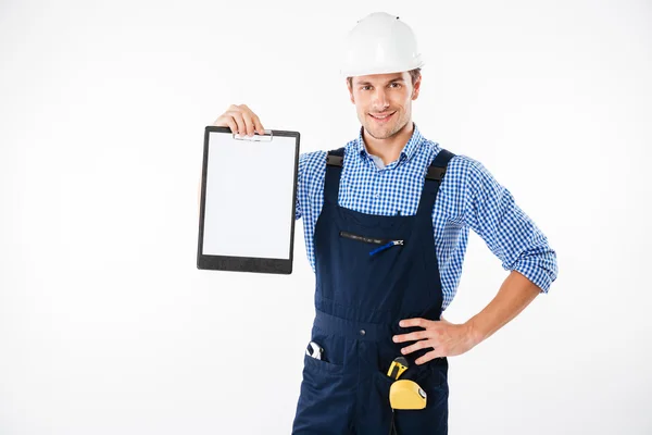 Lächelnder gutaussehender Bauarbeiter zeigt leeres Blatt Papier auf Klemmbrett — Stockfoto