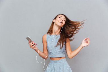 Mutlu kaygısız kadın dans ve akıllı telefondan müzik dinliyor