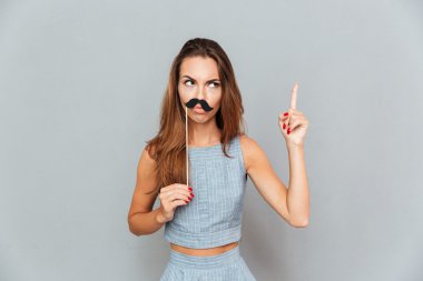 Bıyıklı ciddi eğlenceli genç kadın işaret ediyor