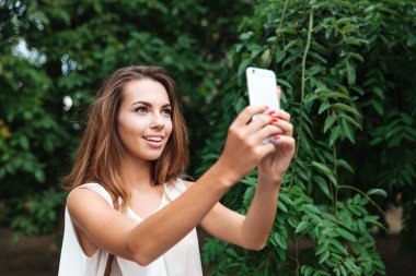 Genç güzel esmer kadın selfie ile smartphone açık havada yapma