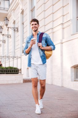 Sırt çantası yla yürüyen ve şehirde kahve içen adam