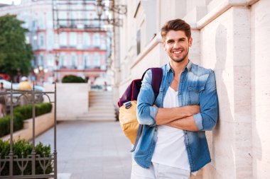 Sırt çantası ve kolları katlanmış gülümseyen rahat adam