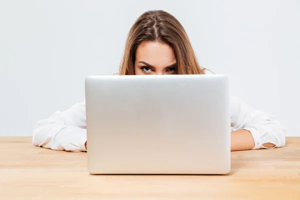 Young brunette woman hiding behind her laptop — Stockfoto