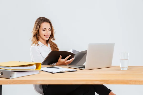 Feliz bela jovem empresária usando laptop e trabalhando com douments — Fotografia de Stock