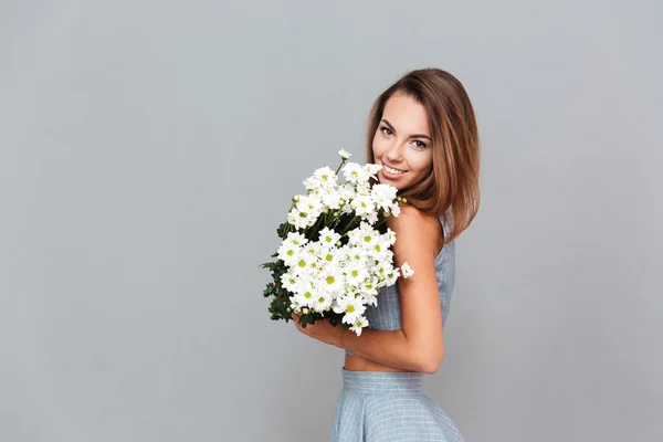 Jovem encantadora alegre de pé e segurando buquê de flores — Fotografia de Stock