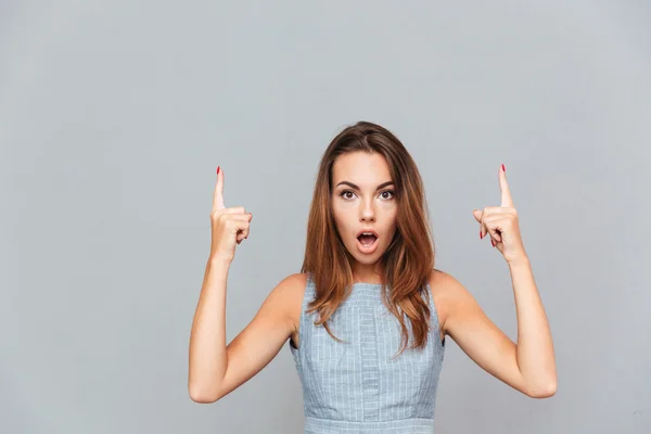 Förvånad chockad ung kvinna som pekar upp med båda händerna — Stockfoto