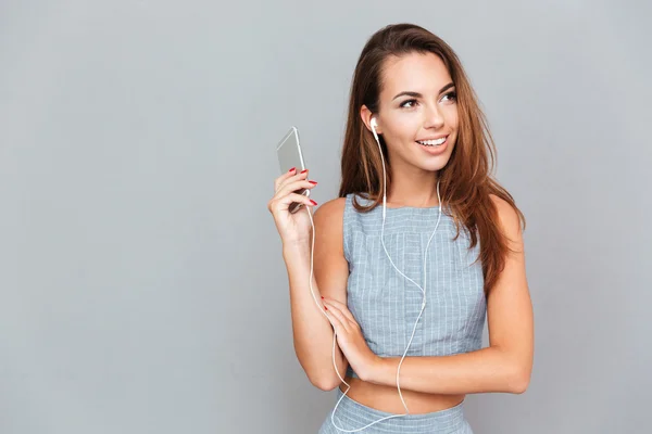 Souriant jeune femme mignonne à l'écoute de la musique du téléphone portable — Photo