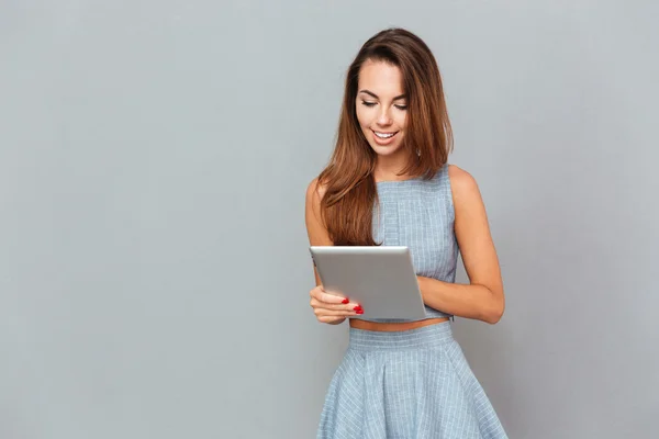 Joyeux belle jeune femme debout et en utilisant la tablette — Photo