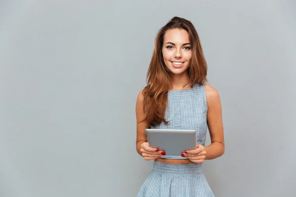Portret szczęśliwego śliczna młoda kobieta stoi i za pomocą tabletu — Zdjęcie stockowe