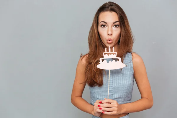 Bastante linda joven mujer soplando en accesorios de pastel de cumpleaños — Foto de Stock