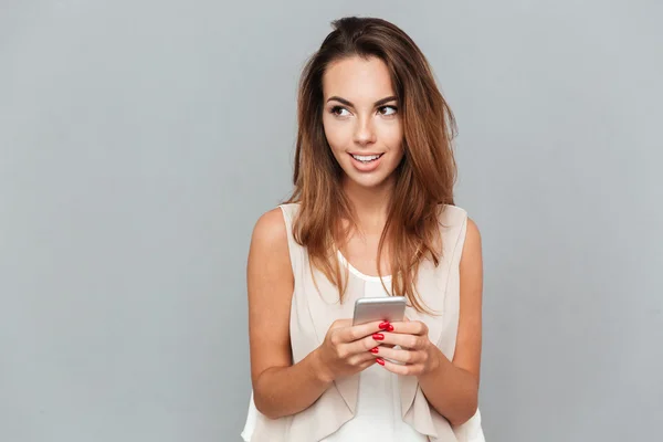 Usměvavá mladá žena drží mobilní telefon — Stock fotografie