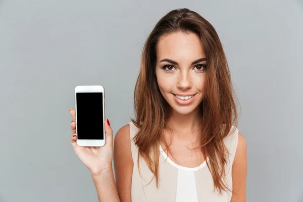 Retrato de una mujer sonriente mostrando la pantalla del teléfono inteligente en blanco — Foto de Stock
