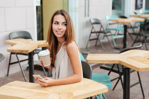 Cep telefonu kullanarak ve açık kafede kahve içme kadın — Stok fotoğraf
