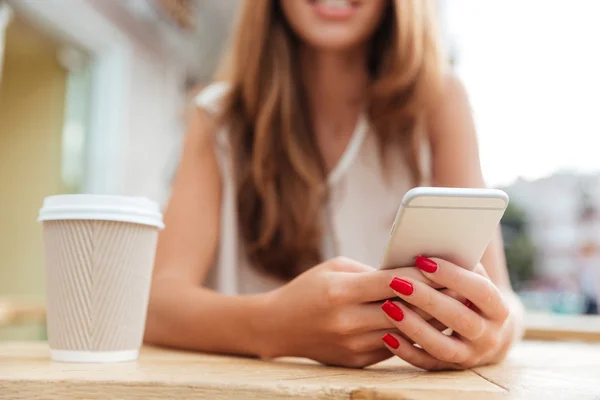 Imagen recortada de la encantadora mujer joven utilizando el teléfono inteligente en la cafetería — Foto de Stock