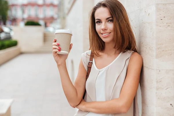 快乐的女人抱着拿掉咖啡，看着相机 — 图库照片