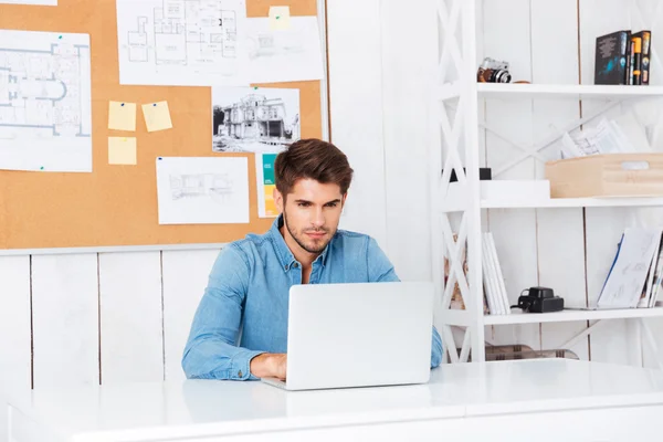 Fundersam stilig skäggiga casual affärsman som sitter med laptop — Stockfoto