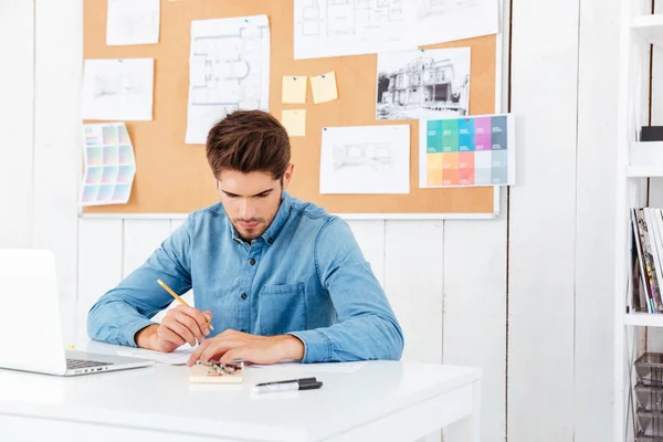 Joven empresario concentrado sentado y escribiendo a la mesa — Foto de Stock