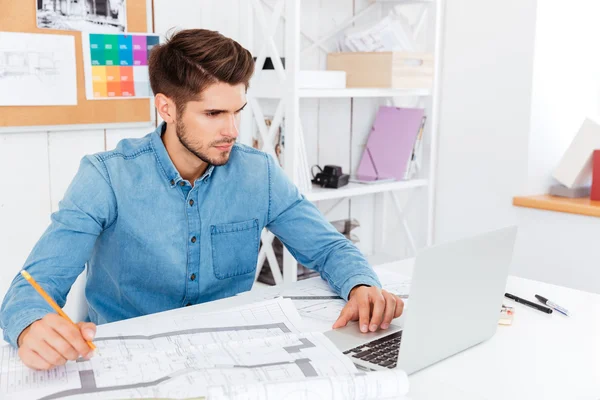 Concntrated ung affärsman med dokument och laptop på kontoret — Stockfoto