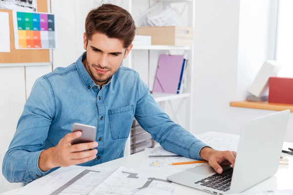 Lachende jonge zakenman in glazen usingat workplce — Stockfoto