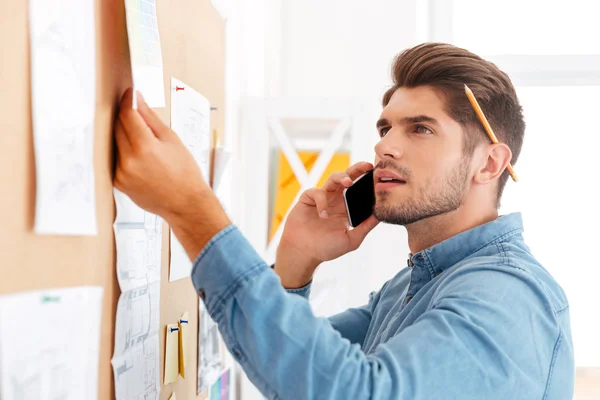 Biznesmen, patrząc na tablicy zadań i rozmawia przez telefon — Zdjęcie stockowe