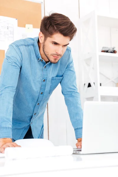Tankfull ung affärsman tittar på laptop i office — Stockfoto