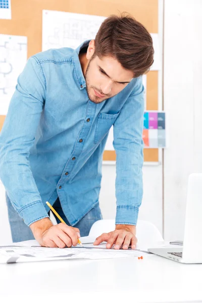 Молодий бізнесмен робить нотатки, стоячи за офісним столом — стокове фото
