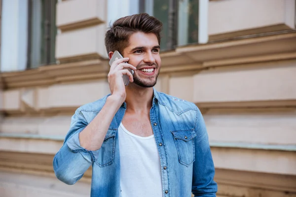 Smiling man standing on street and talking by cell phone — Stock Photo, Image