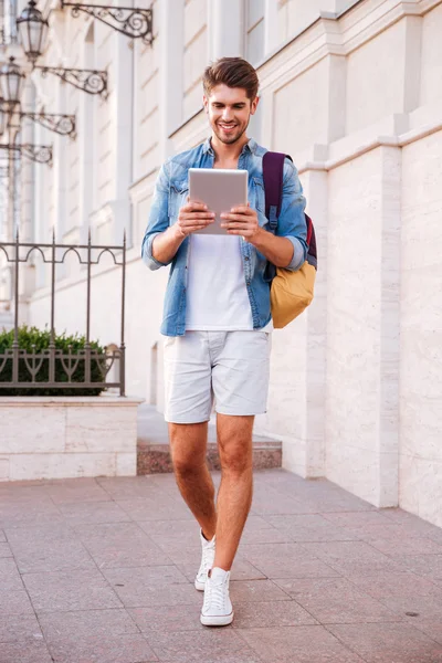 Hombre con mochila caminando y usando la tableta en la calle — Foto de Stock
