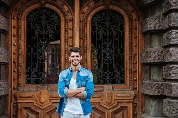 Sorrindo homem de pé na frente da bela porta de madeira — Fotografia de Stock