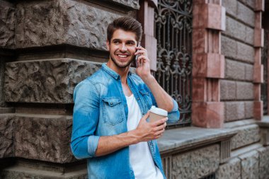 Öğrenci cep telefonuyla konuşuyor ve kahve içiyor