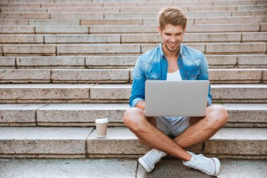 Young man using laptop while sitting on the staircase outdoors
