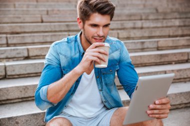 İçen adam kahveyi alıp dışarıda tablete bakıyor